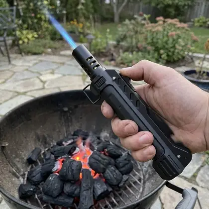 TacFlame jet flame lighting charcoal in a kettle grill in a backyard
