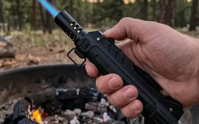 TacFlame blue jet flame lighting a fire pit in a pine forest at sunset